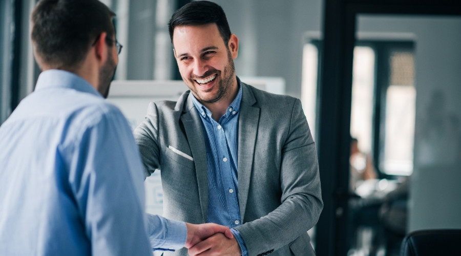 ertrauensvoller Immobilienverwalter in einer Besprechung – Geschäftspartner schließen eine erfolgreiche Vereinbarung. Freundliche und professionelle Atmosphäre im Büro, die eine positive Beziehung zwischen Immobilienverwalter und Eigentümern widerspiegelt. Symbol für Vertrauen und Kompetenz in der Immobilienverwaltung.