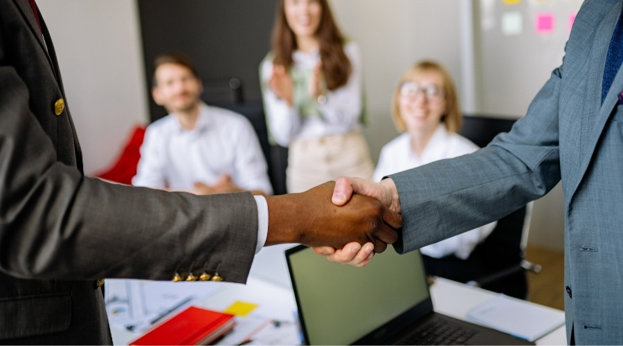 Erfolgreicher Handschlag bei einer Eigentümerversammlung – Mediator und Eigentümer erreichen eine Einigung. Professionelle Besprechung im Büro mit Beteiligten, die eine Lösung für Konflikte in der Hausgemeinschaft finden. Symbol für Zusammenarbeit und Mediation in der Immobilienverwaltung.